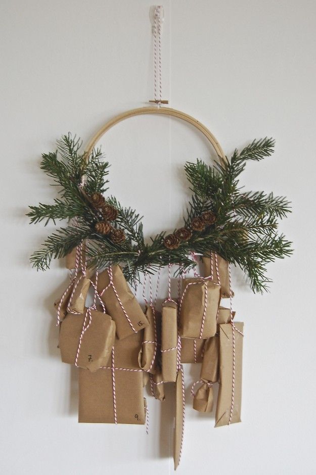An embroidery hoop holds the greenery and the advent gifts tied on with red and white baker's  twine.